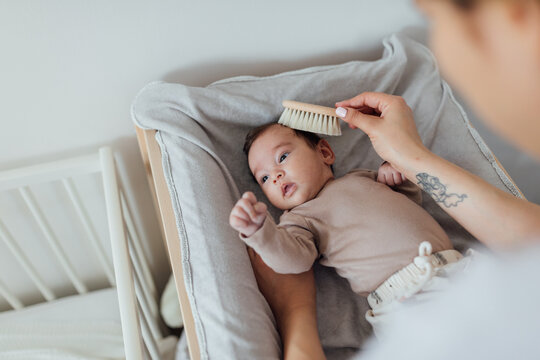 Mother Brushing Hair Of A Newborn