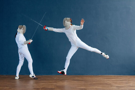 Energetic fencers fighting in gym