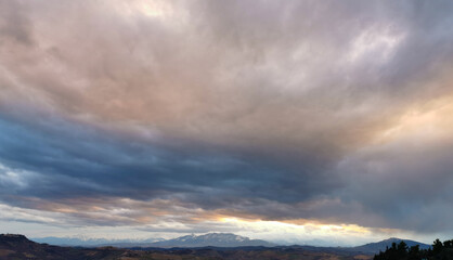 Grandi nuvole grigie e rosa con i monti le colline e la valli degli Appennini all’orizzonte