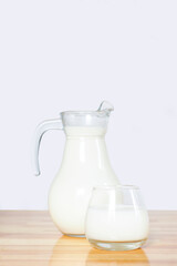 milk in a glass and a jug on a wooden table on a gray background. copy space..