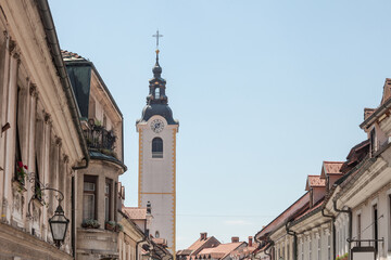 Fototapeta na wymiar Church tower, cerkveni stolp, on the Zupinjska cerkev, a baroque roman catholic church in the center of Kamnik, Slovenia, on the main street of the city, Sutna, in a sunny summer afternoon...