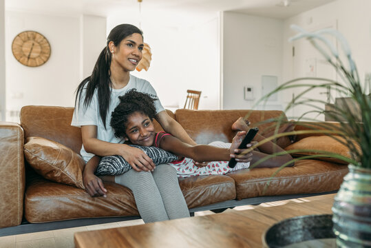 Black mother and daughter watching TV together