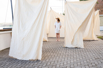 Woman In Background Of Many Hanged Bed Linen