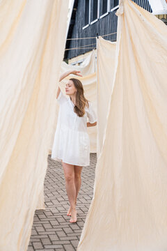 Woman Dancing In Background Of Hanged Bed Linen