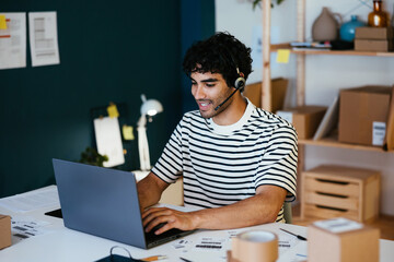 Cheerful operator with headset using laptop in delivery office