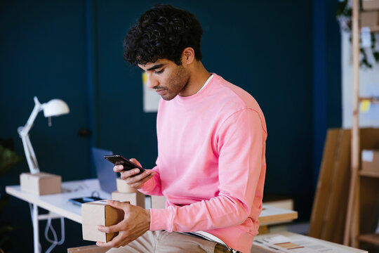 Hispanic guy scanning bar code on box in office