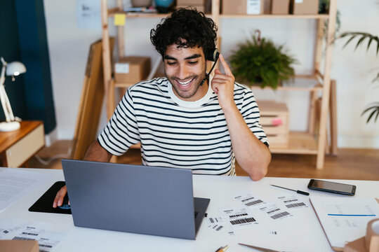 Happy man using laptop and speaking with client in delivery office