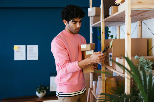 Hispanic worker scanning parcels on shelf