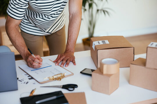Crop man signing delivery documents near boxes