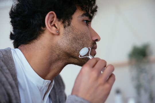 Hispanic man using jade roller