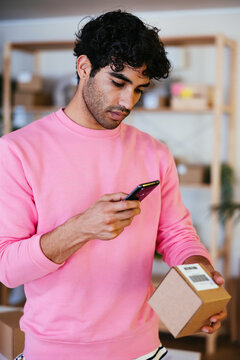 Hispanic male scanning bar code on parcel