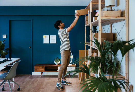 Hispanic worker taking box from shelf