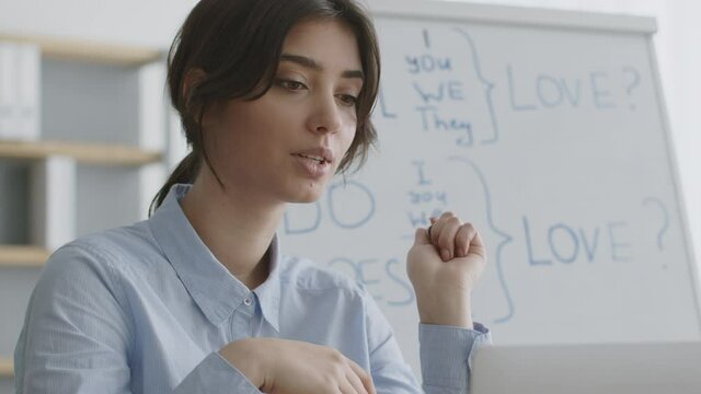 Foreign language tutoring concept. Young woman teacher explaining English grammar rules to student online