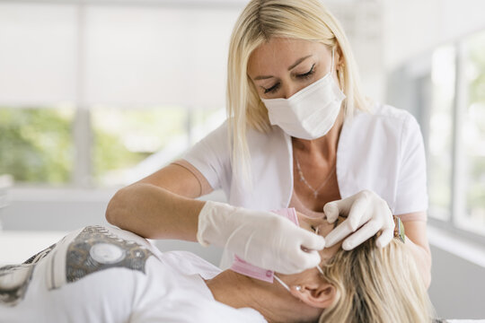 Female doctor preparing eyes for a micropigmentation intervention.