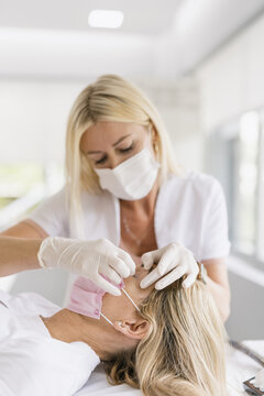 Female doctor preparing eyes for a micropigmentation intervention.