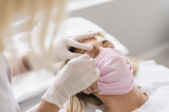 Female doctor preparing eyes for a micropigmentation intervention.
