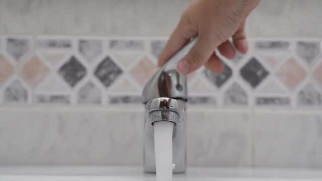 A hand turning on and off the tap for running water in HD