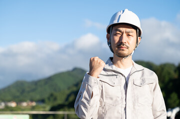 とても真剣な眼差しでガッツポーズの作業着の中年男性