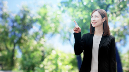 木々の前に立つビジネスウーマン