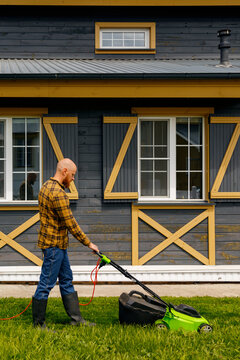 Bearded Guy Mowing Lawn Outside Cottage