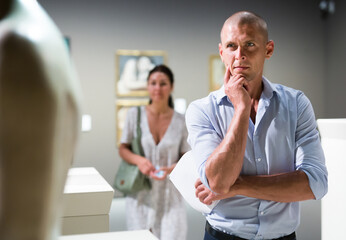 Obraz premium Adult European man standing in museum hall and watching exposition
