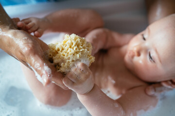 Mother bathing her baby in the bathtub