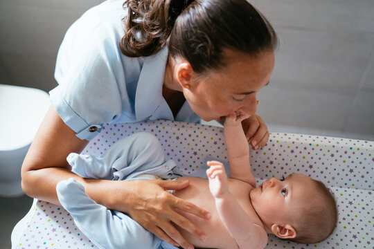 Mother Playing With A Baby In A Changing Table At Home