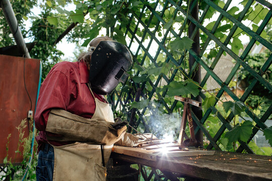 Man welding metal detail in yard