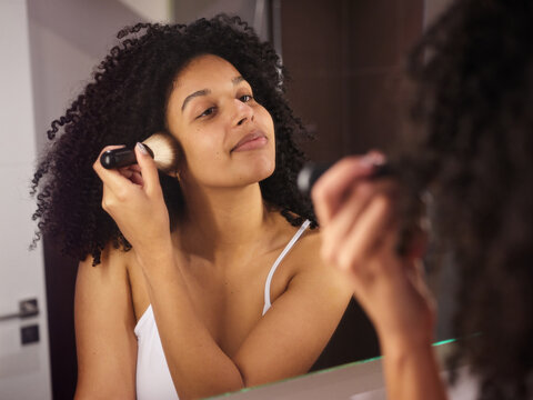 Content female doing contouring with cosmetic