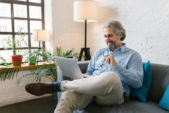 Senior businessman sitting at the couch in the office using his laptop