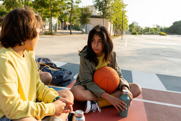 Friends relaxing sitting on the basketball court