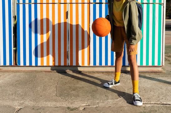 Kid in front of a colorful wall voting a basketball