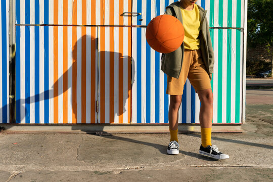 Kid in front of a colorful wall holding a basketball