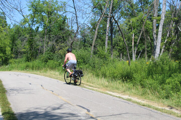 Sweaty shirtless man riding a bicycle on the North Branch Trail at Miami Woods in Morton Grove, Illinois