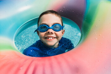 Boy wearing goggles in pool float.