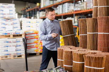 Male buyer chooses decorative wicker fence in hardware store. High quality photo
