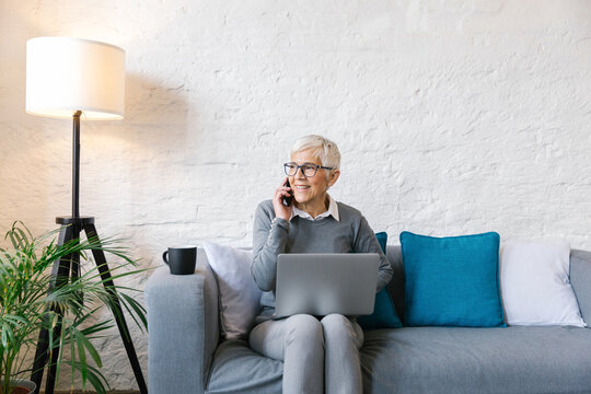 Senior businesswoman sitting at the couch in the office using her smartphone