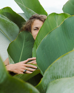 Woman stands in a thicket of large tropic leaves