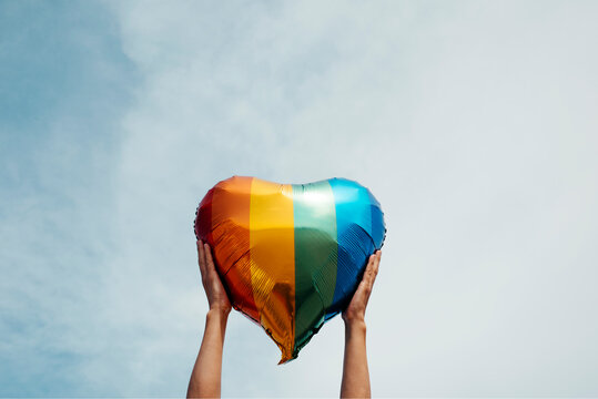 man grabbing a rainbow heart-shaped balloon