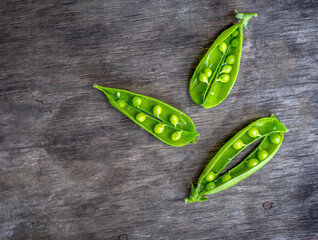 Opened pods of young green peas on a wooden table