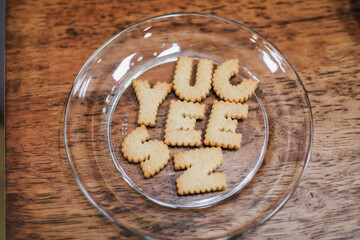 Plate with alphabet Biscuits on wooden table with bluer background. Top view photo.