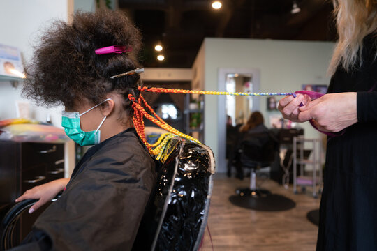 Stylist braids rainbow hair for young client