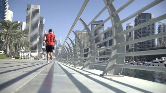 a man is engaged in a morning jog along the embankment of Dubai Marina
