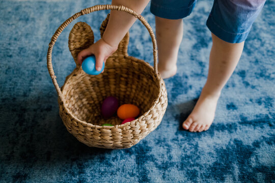 Anonymous child putting easter egg into basket