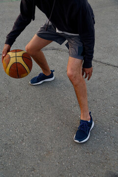 Crop sportsman dibbling basketball ball