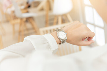 fashionable wearing stylish looking at luxury watch on hand check the time at workplace.concept for...