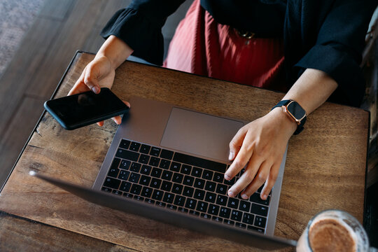 Anonymous Arab woman connecting by bluetooth a mobile phone with a laptop