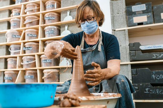 Middle aged potter spreading water on clay vase
