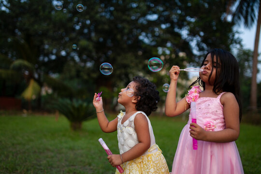 Little Indian girls playing with soap bubbles in a park