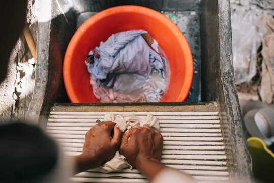 Faceless person doing laundry by hands in concrete reservoir